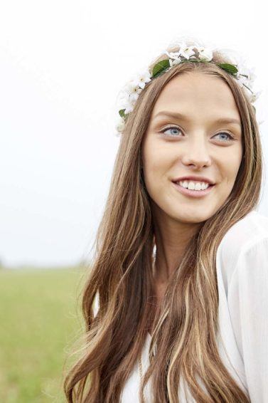 Modelo com cabelo longo e coroa de flores brancas ilustra matéria sobre Cortar o cabelo antes do casamento