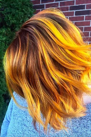 Mulher de cabelos coloridos com mechas laranjas e amarelas