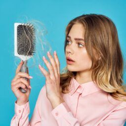 mulher com cabelo caindo muito olhando pra escova cheia de cabelo