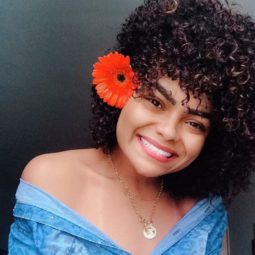 mulher de cabelo com permanente afro com flor