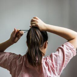 mulher de costas prendendo o cabelo