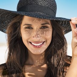 Mulher na praia com chapéu preto