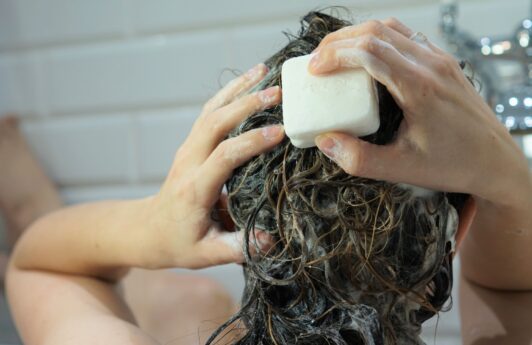 mulher lavando o cabelo com sabonete