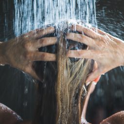 Mulher lavando os cabelos debaixo do chuveiro