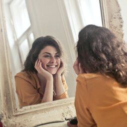 mulher sorrindo se olhando no espelho