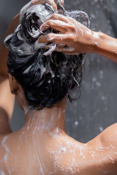 mulher esfregando o cabelo com shampoo