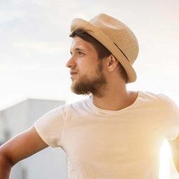 Homem com chapéu, cabelo curto e barba no verão