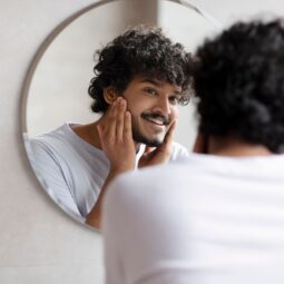 homem com barba se olhando no espelho