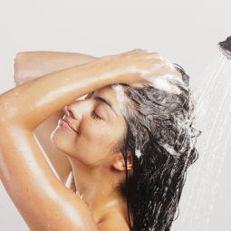 Mulher passa shampoo nos cabelos e faz espuma durante o banho