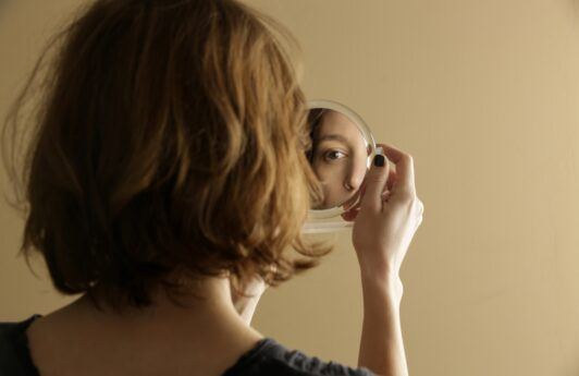 mulher se olhando em um espelho pequeno