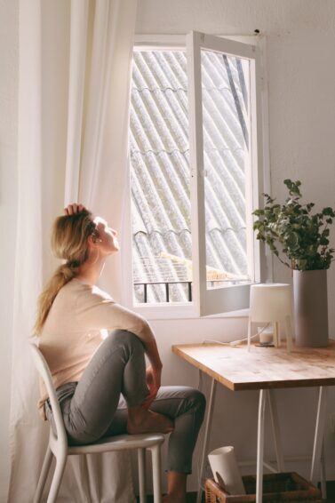 mulher sentada do lado da janela tomando sol