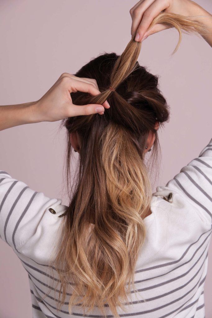 woman with ombre hair creates french braid and secures second ponytail