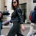 a woman walking on a street wearing leather black jacket and grey pants on