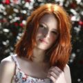 a ginger woman with shirt haircut wearing a flowery dress in a park