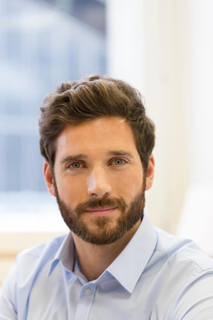 Foto Stock Close up portrait of attractive young brunette man with trendy  hairstyle and trimmed beard posing at white studio wearing formal shirt and  suspenders feeling confident about upcoming job interview 