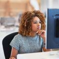 an afro woman with blonde curly hair sitting at her office checking the computer