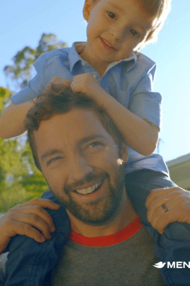 a bearded man standing outside playing with a kid