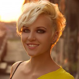 a blonde woman with short pixie hair cut standing outside