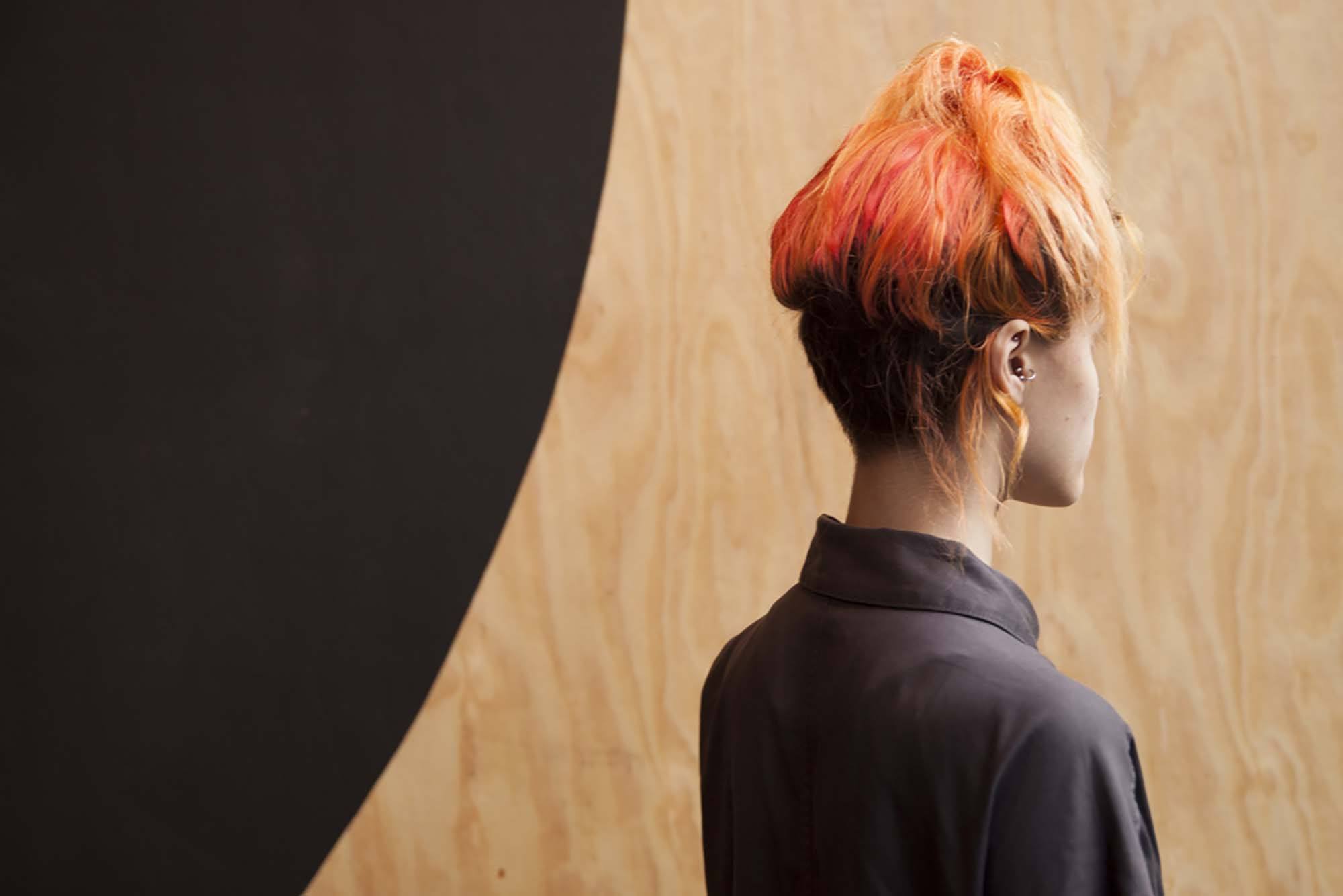 Beautiful women with blood orange hair worn in a high ponytail