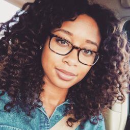 a woman with curly hair wearing glasses in a car