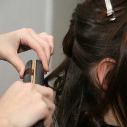 Hair dresser adding waves to short hair using a flat ironer