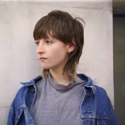 model with funky short hair in a mullet style, wearing denim