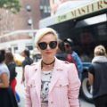 a woman with platinum pixie hair standing outside next to a bus