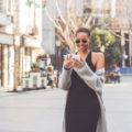 a bautiful black woman walking on the street while playing with her smartphone