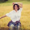 a cheerful woman having fun in a savana wearing a hat