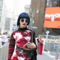 a woman walking in a city wearing reddish dress with a short blue hair
