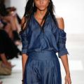 a female model with long black hair walking on a catwalk wearing blue dress