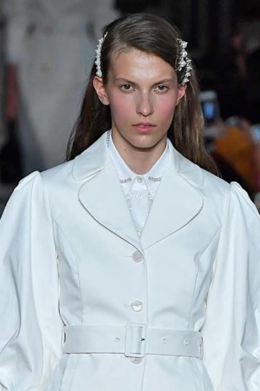 a female fashion model walking on a runway wearing white shirts