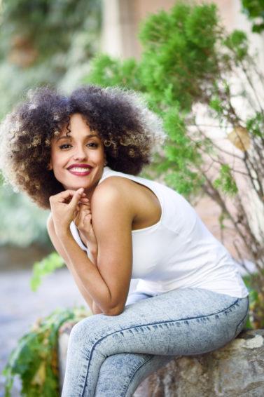 a cute afro woman sitting in a garden