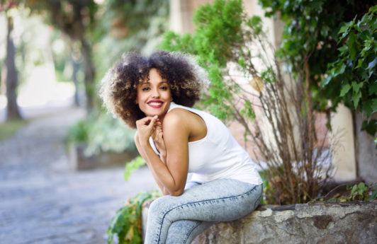 a cute afro woman sitting in a garden