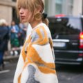 a woman wearing colorful coat crossing the street in a city
