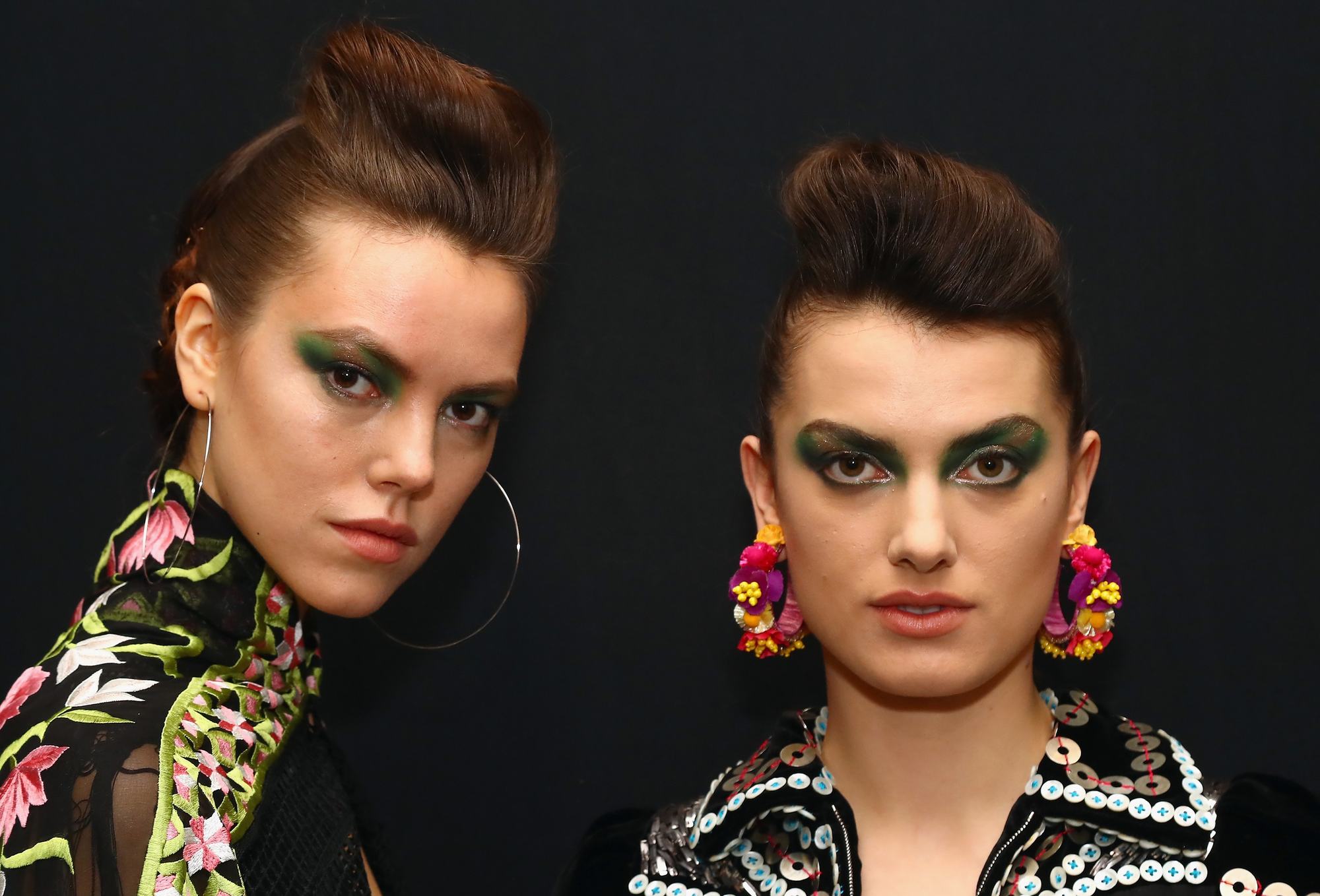two female models posing on the black background with slickback hair