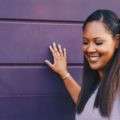 a beautiful long hair black woman touching purple wall