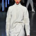 a female fashion model wearing white sweater with long black hair on a runway