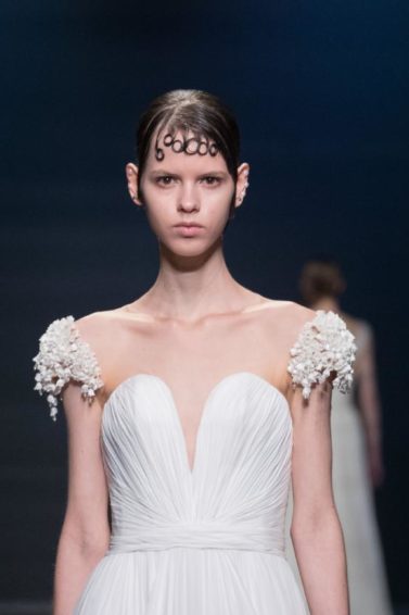 a photo pf female fashion model in a white wedding dress walking on the catwalk with artsy bangs on her hair