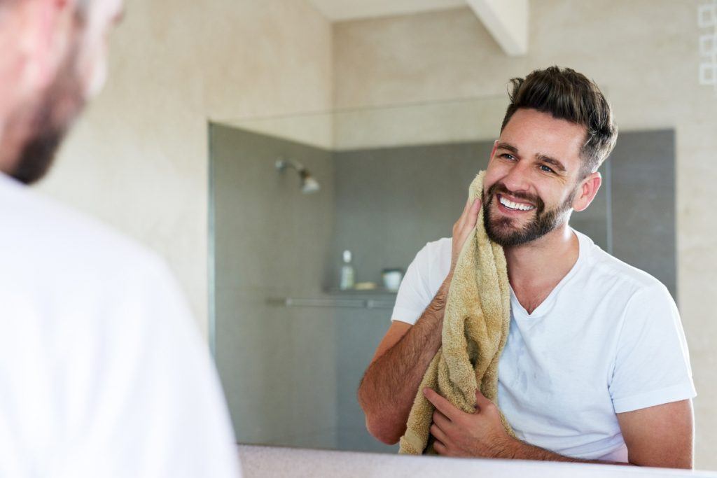 Man looking in the mirror with a towel