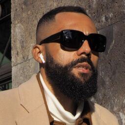 Man with a high taper fade haircut and a beard wearing sunglasses outdoors
