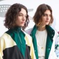 close up shot of two models backstage with wavy short hair, wearing tracksuit jackets and posing