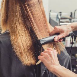 Woman getting hair hair straightened in a salon
