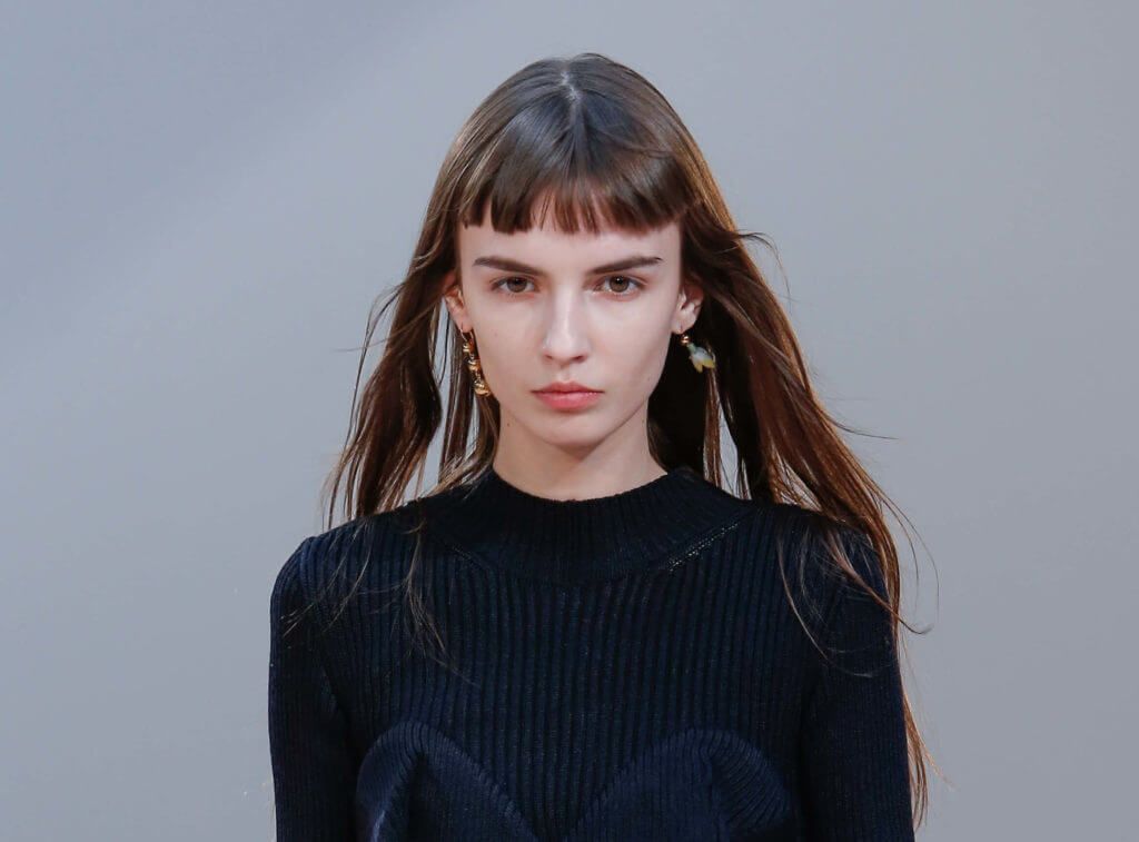 woman on the runway with a micro bangs hairstyle on long brown hair