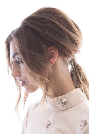 Elegant updos: side view of woman with light brown medium length straight hair styled into a '60s-inspired Bardot ponytail with long bardot bangs