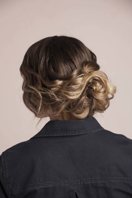 Messy bun: Back view of a brunette woman with a curly bun updo