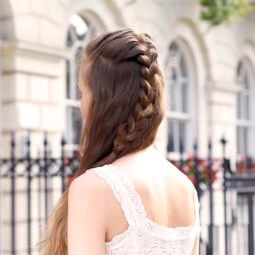 a rear view of braided long brown hair of a woman standing on the sideway