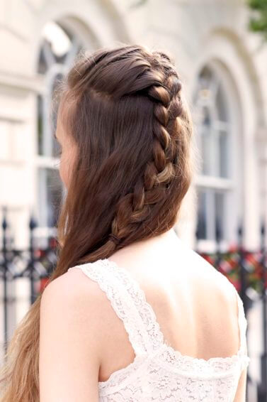 a rear view of braided long brown hair of a woman standing on the sideway