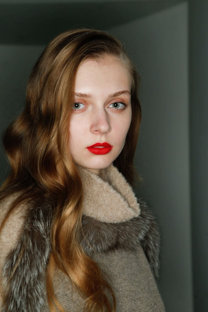 front view of a woman with red lipstick and honey blonde hair, sun kissed brown waves