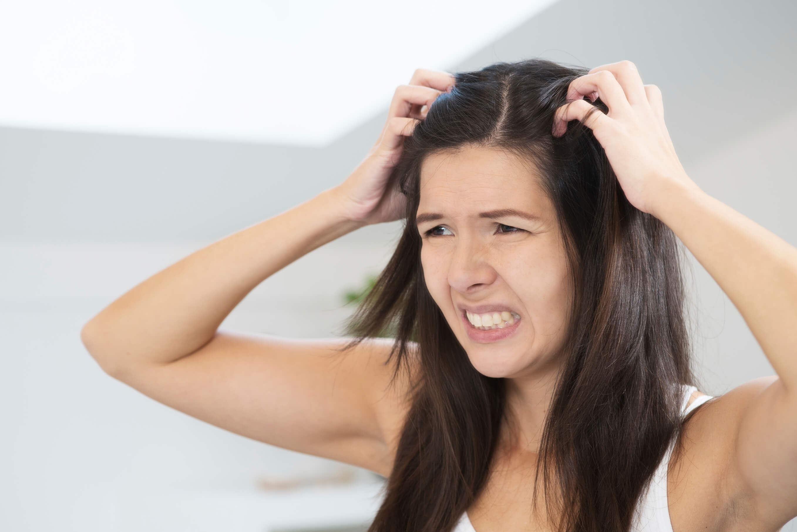women with dark brown hair scratching her dry scalp